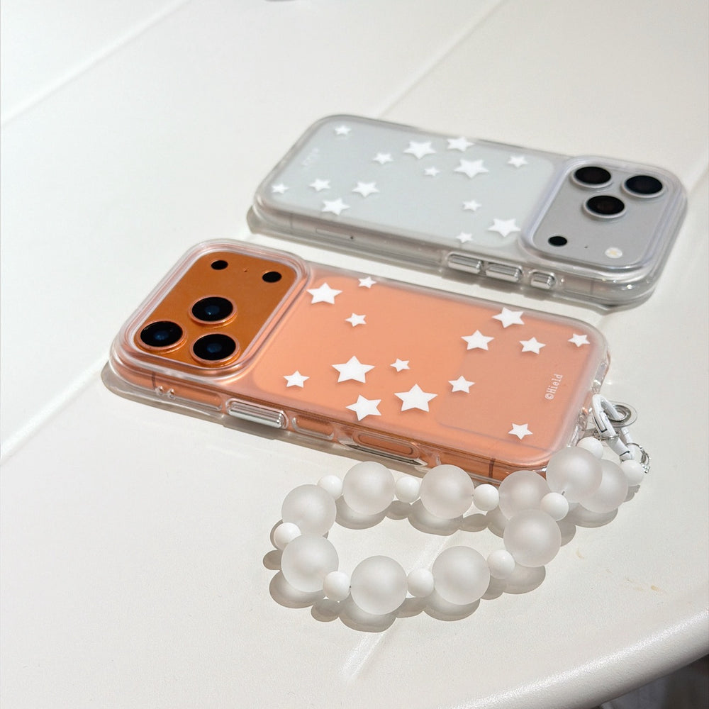 Two aesthetic star-patterned iPhone cases in orange and silver placed flat on a white surface with a beaded charm.