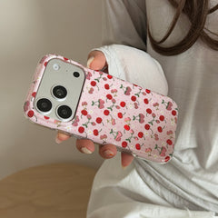 A side angle view of a person holding a shockproof pink cherry phone case against a white shirt.