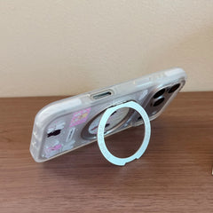 Close-up of fingers holding a clear anime phone case using the built-in silver metal ring stand holder.