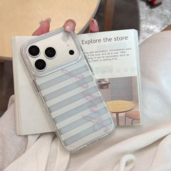 A hand with star-patterned nail art holding a silver and white vertical striped Angel iPhone case over an open textbook.