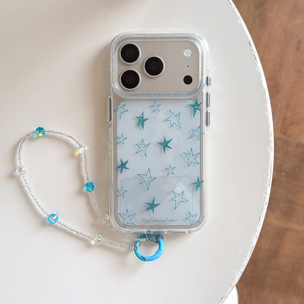 Product shot of a silver Y2K star clear phone case with a beaded strap on a white background.
