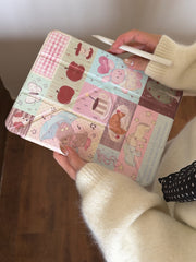 A hand holding a closed soft girl aesthetic patchwork iPad folio case at an angle while holding a white stylus pencil.