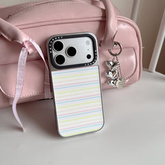A sweet pastel stripe phone case standing next to a soft pink handbag with a heart keychain.
