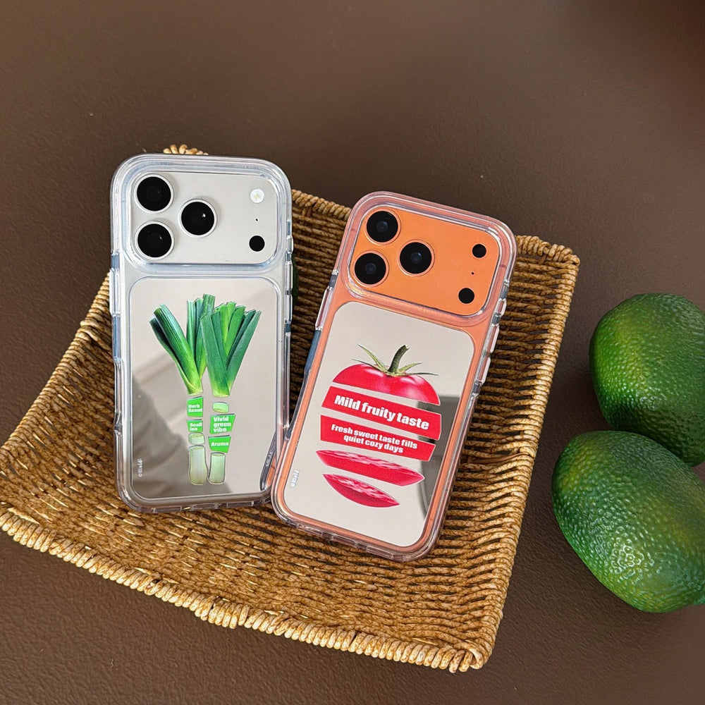 Tomato and green scallion mirror phone cases displayed neatly inside a woven rattan basket with fresh limes.