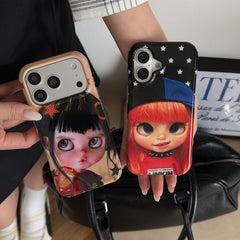 Two big-eye doll iPhone case styles displayed above a black handbag.