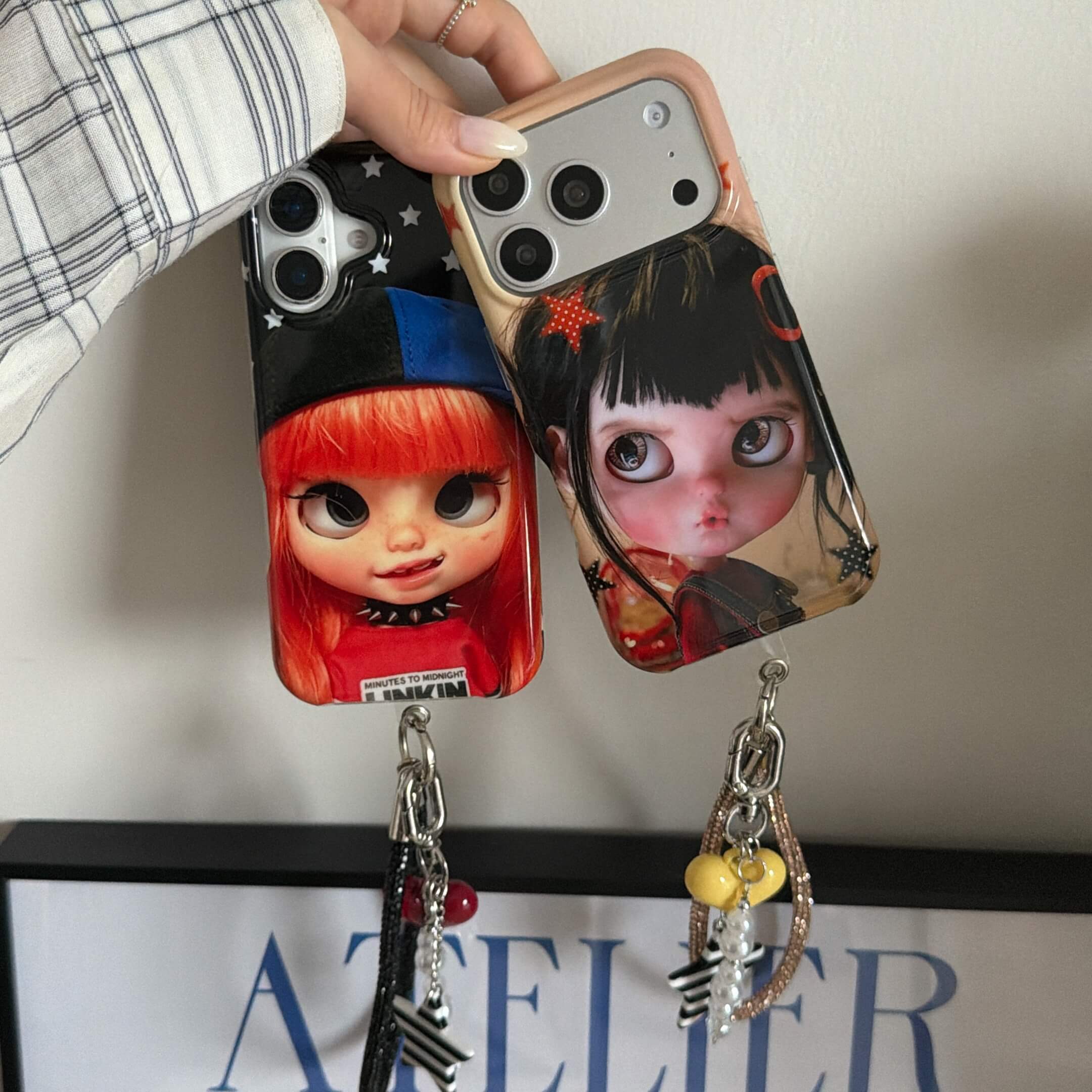 Two Y2K doll iPhone cases with black and champagne charm wrist straps.