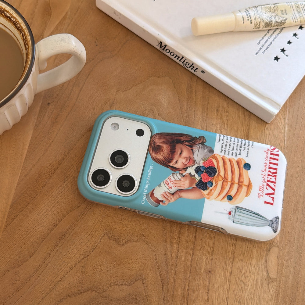 An angled view of a vintage pancake girl phone case on a wooden table next to a coffee mug.