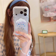 A clear iPhone case with a 3D white cloud and blue twinkle stars resting on an open pastel notebook.