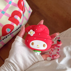A hand holding a 3D cartoon strawberry style AirPods protective shell with a red crystal charm against a checkered bag.