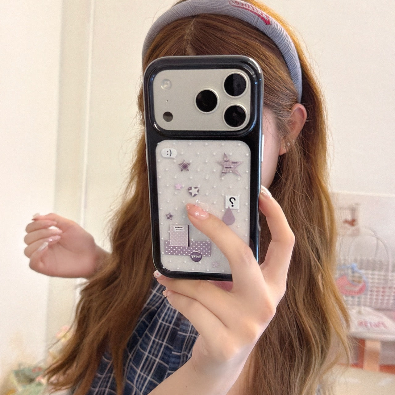 Girl taking a mirror selfie holding a silver Y2K mirror iPhone case with cute star patterns and a black bumper.