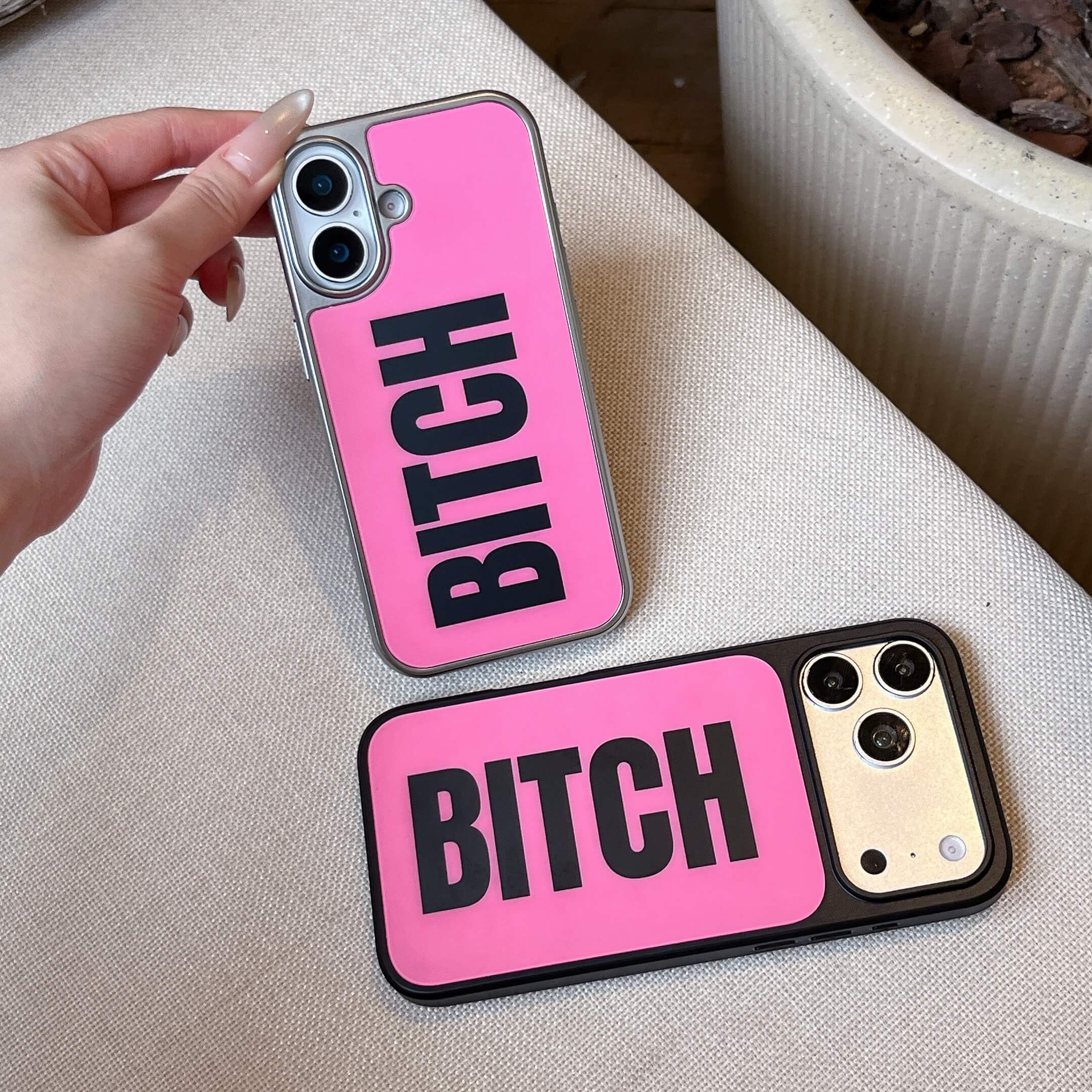 Two hot pink phone cases with bold black BITCH text, one with a silver border and one with a black border.