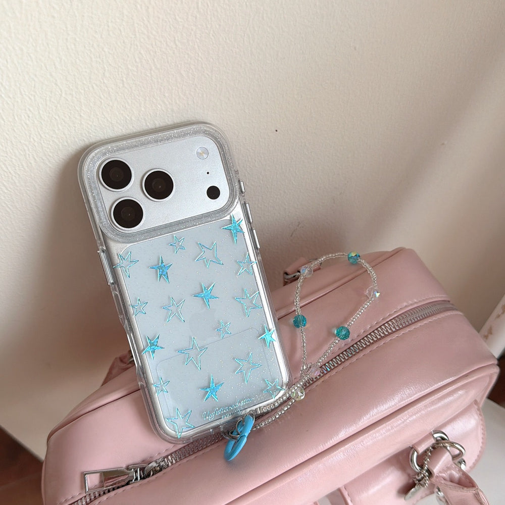 A Y2K clear case with sparkling blue stars leaning on a pastel pink handbag.