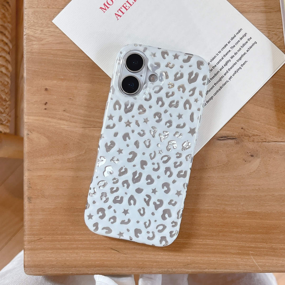 A flat lay of a white Y2K star leopard print iPhone case resting on a card over a wooden surface.